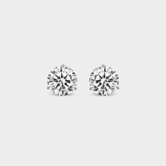 3 Prong Martini Diamond Studs. Close-up of a pair of round diamond earrings on a neutral background. Everyday sized lab diamond stud with modern martini setting in 14K gold perfect for building an ear stack.