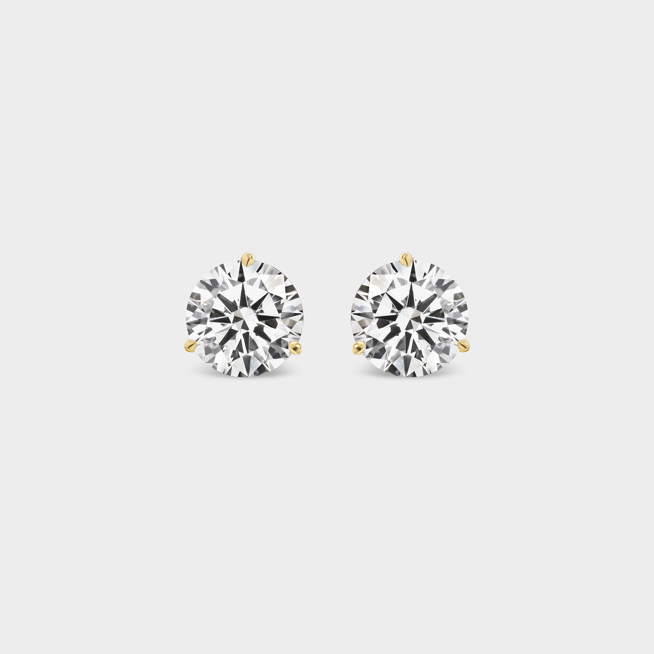 3 Prong Martini Diamond Studs. Close-up of a round diamond earring on a neutral background. Everyday sized lab diamond stud with modern setting in 14K white gold for school, work, events, or nights out. For a sophisticated woman with great taste. 