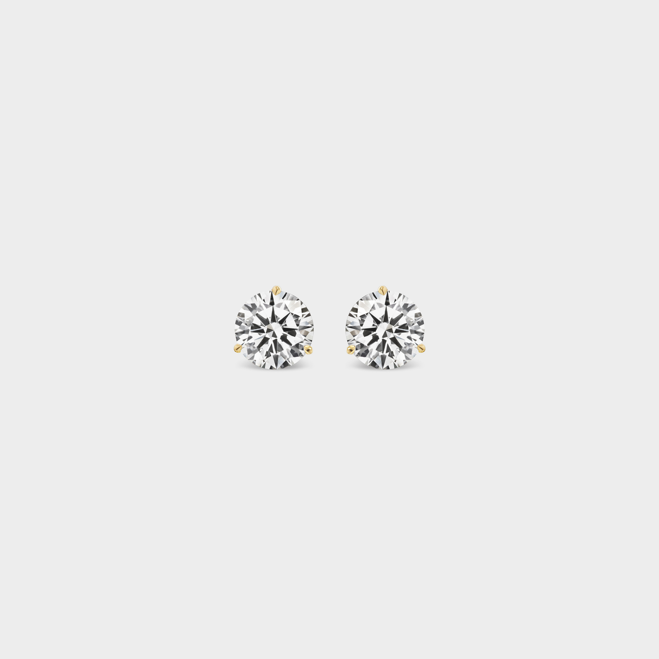 3 Prong Martini Diamond Studs. Close-up of a 0.5 TCW pair of round diamond earrings on a neutral background. Everyday sized lab diamond stud with modern setting in 14K gold perfect for building an ear stack