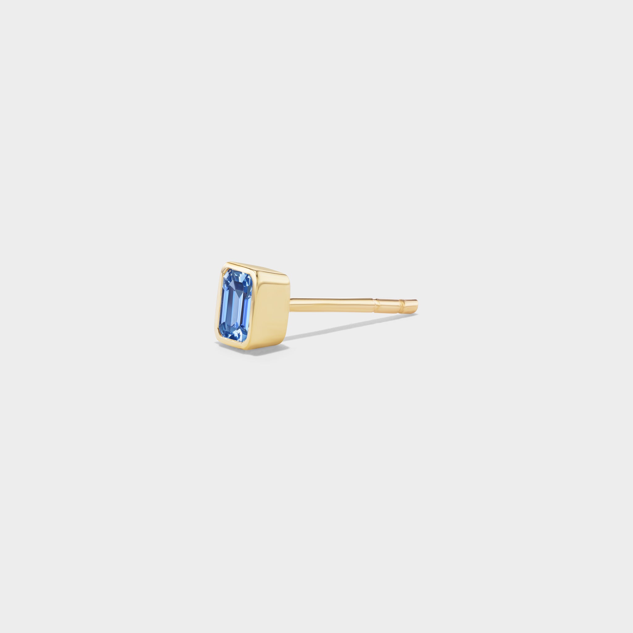 Mini 14k yellow gold stud with an emerald-cut blue sapphire in a sleek bezel setting, ideal for ear stacks.