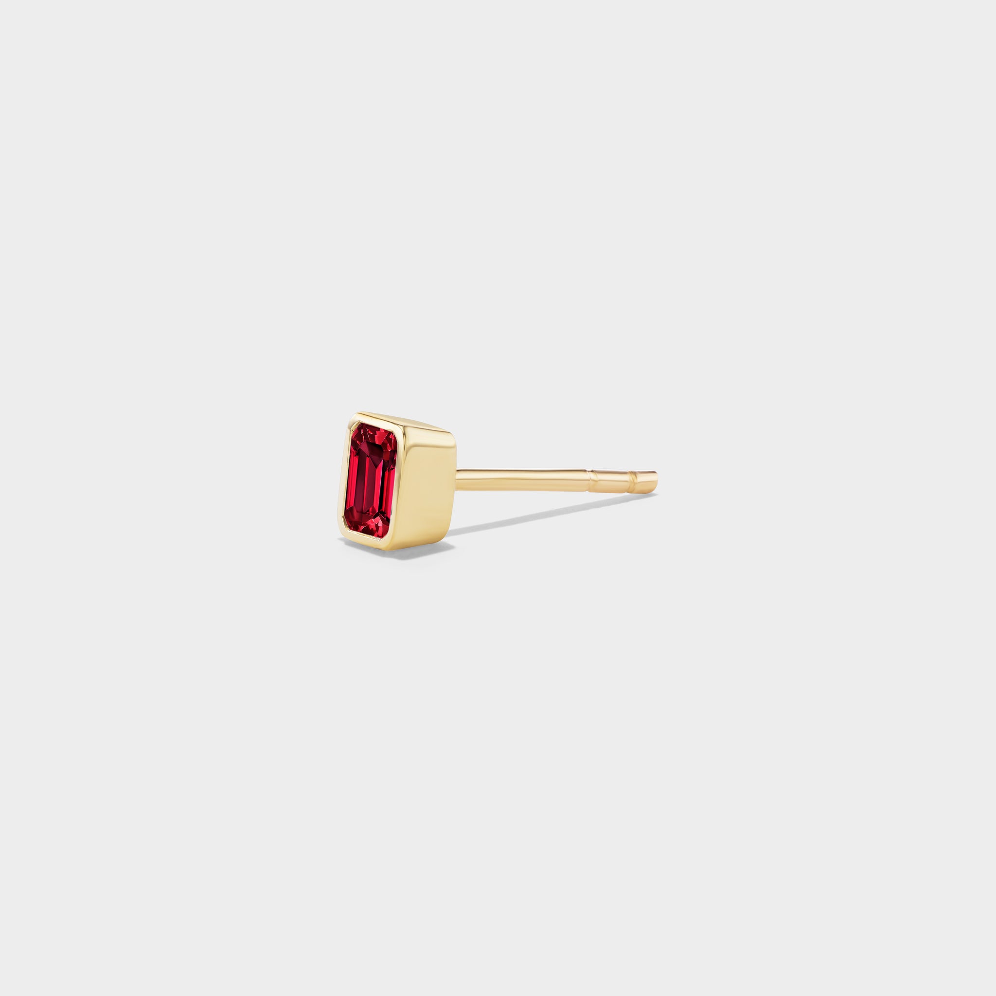 Yellow gold mini stud earring with an emerald-cut ruby in a sleek bezel, perfect for an ear stack.