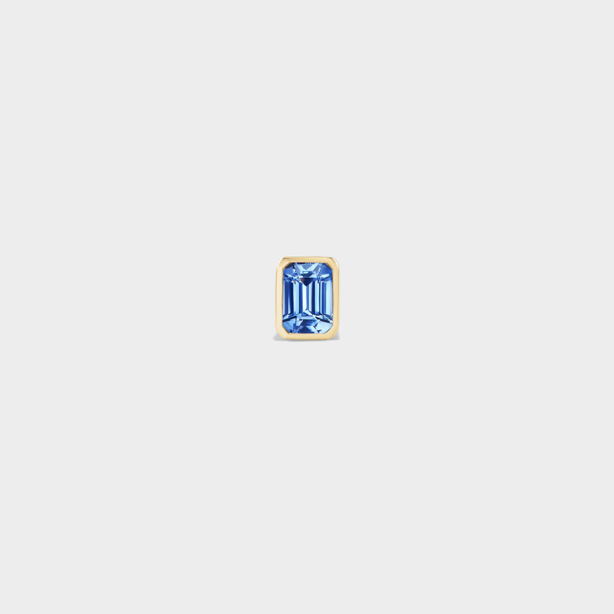 Everyday mini stud earring with an emerald-cut blue sapphire in a sleek 14k yellow gold bezel setting.