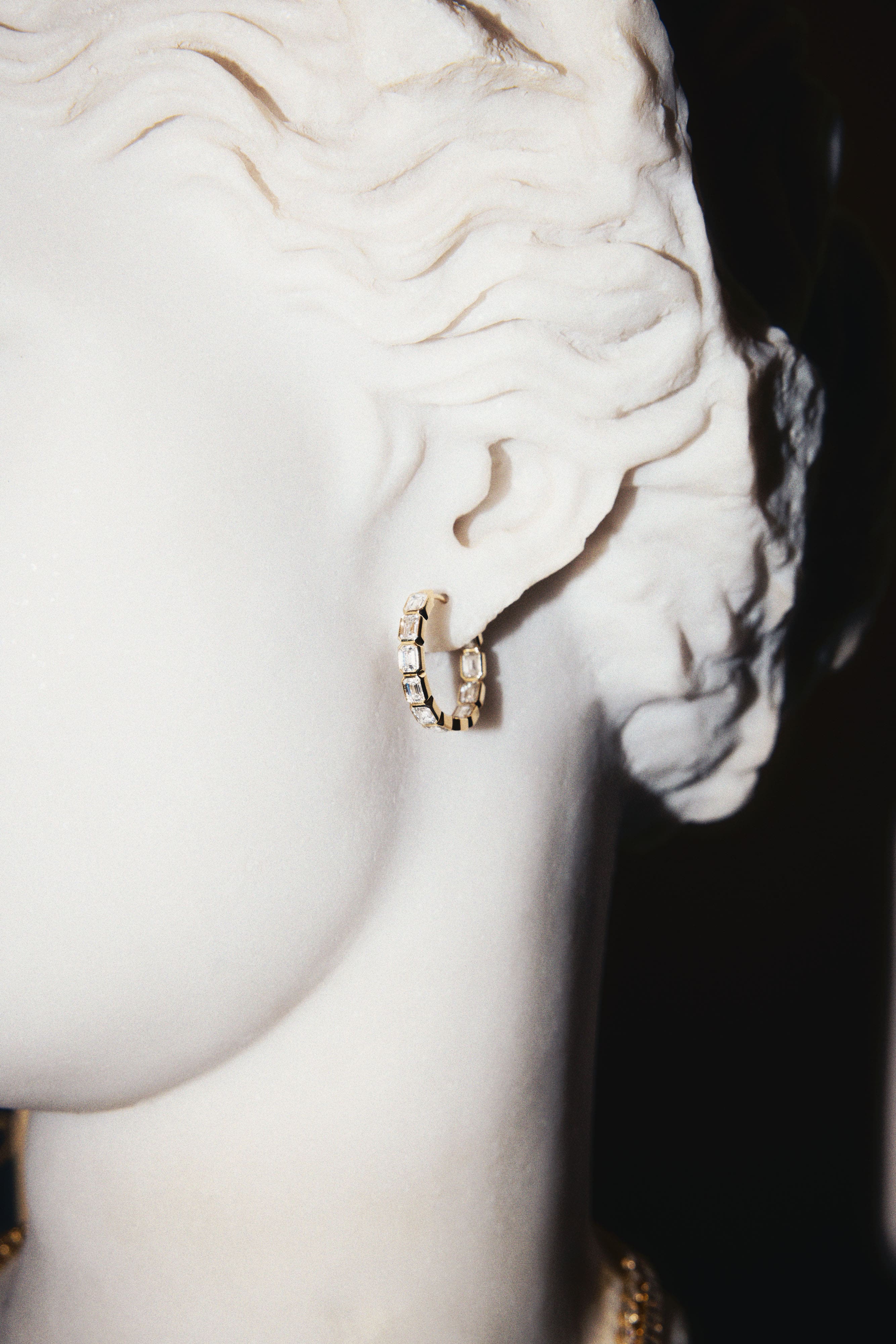 Gold inside-out hoops with emerald-cut lab diamonds on a white marble bust, perfect for everyday wear.