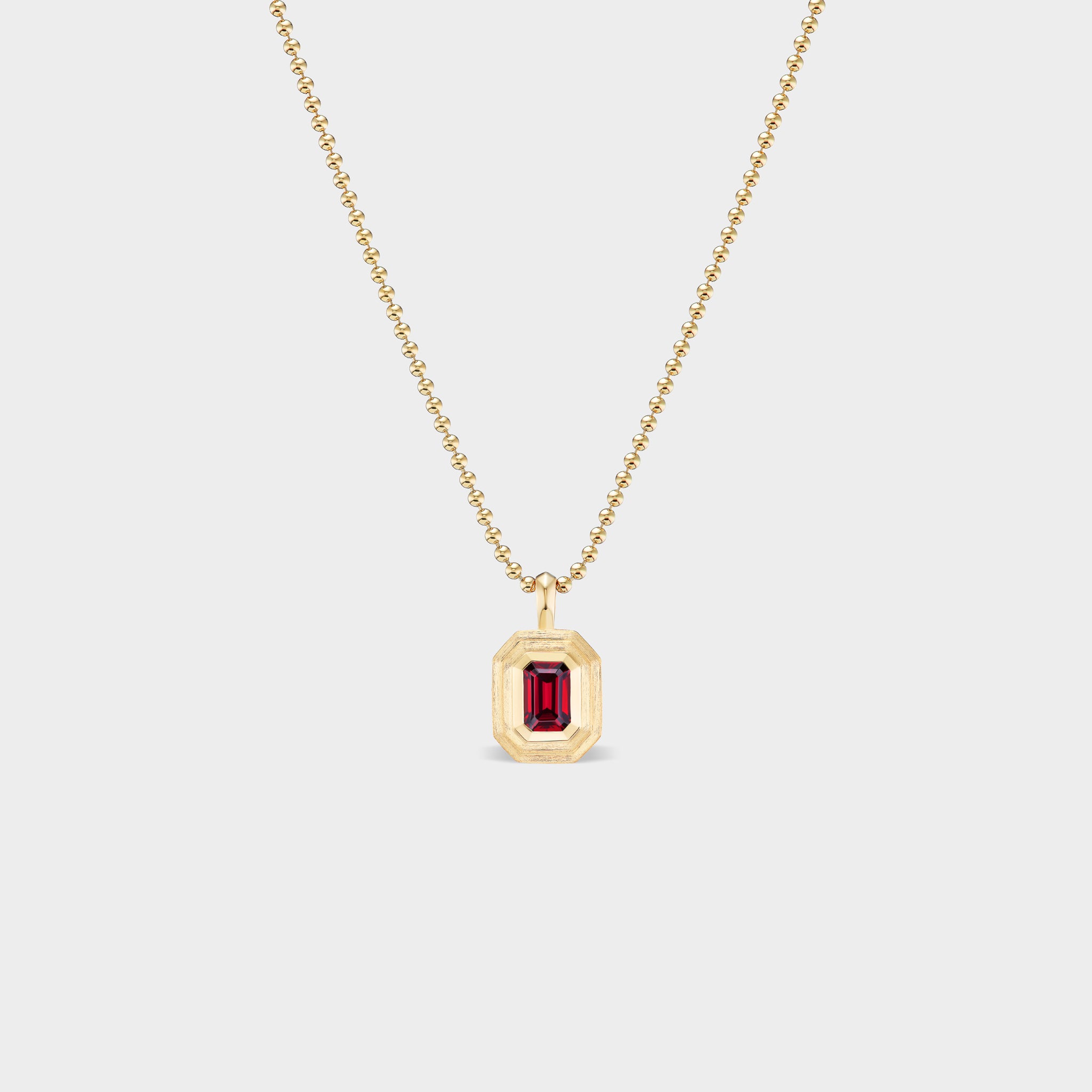 Mini emerald bezel charm in 14K gold with an emerald-cut natural ruby on a ball chain, perfect for everyday wear.