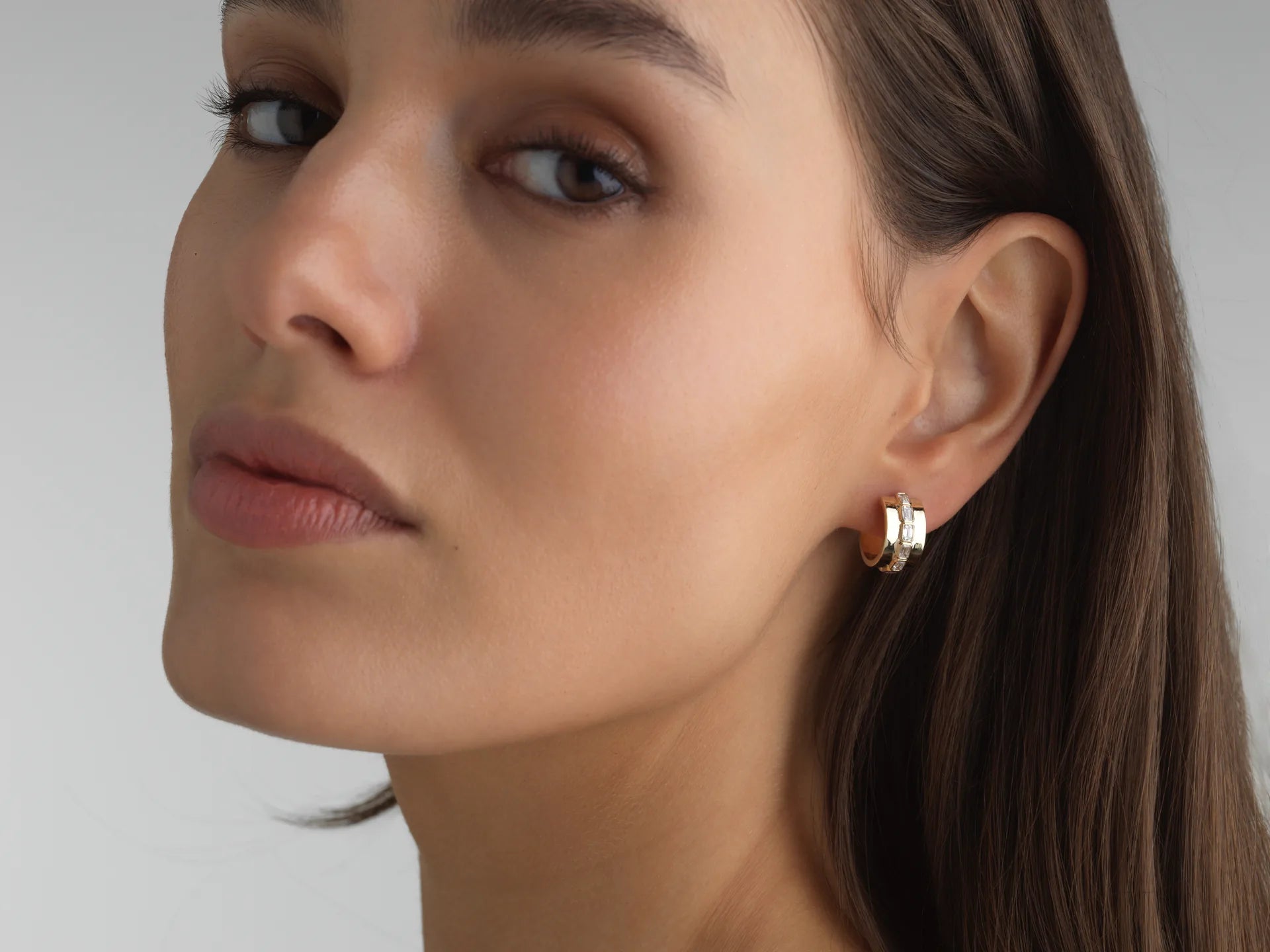 Everyday 14k yellow gold mini hoops with bezel-set emerald-cut lab diamonds, perfect for an ear stack.