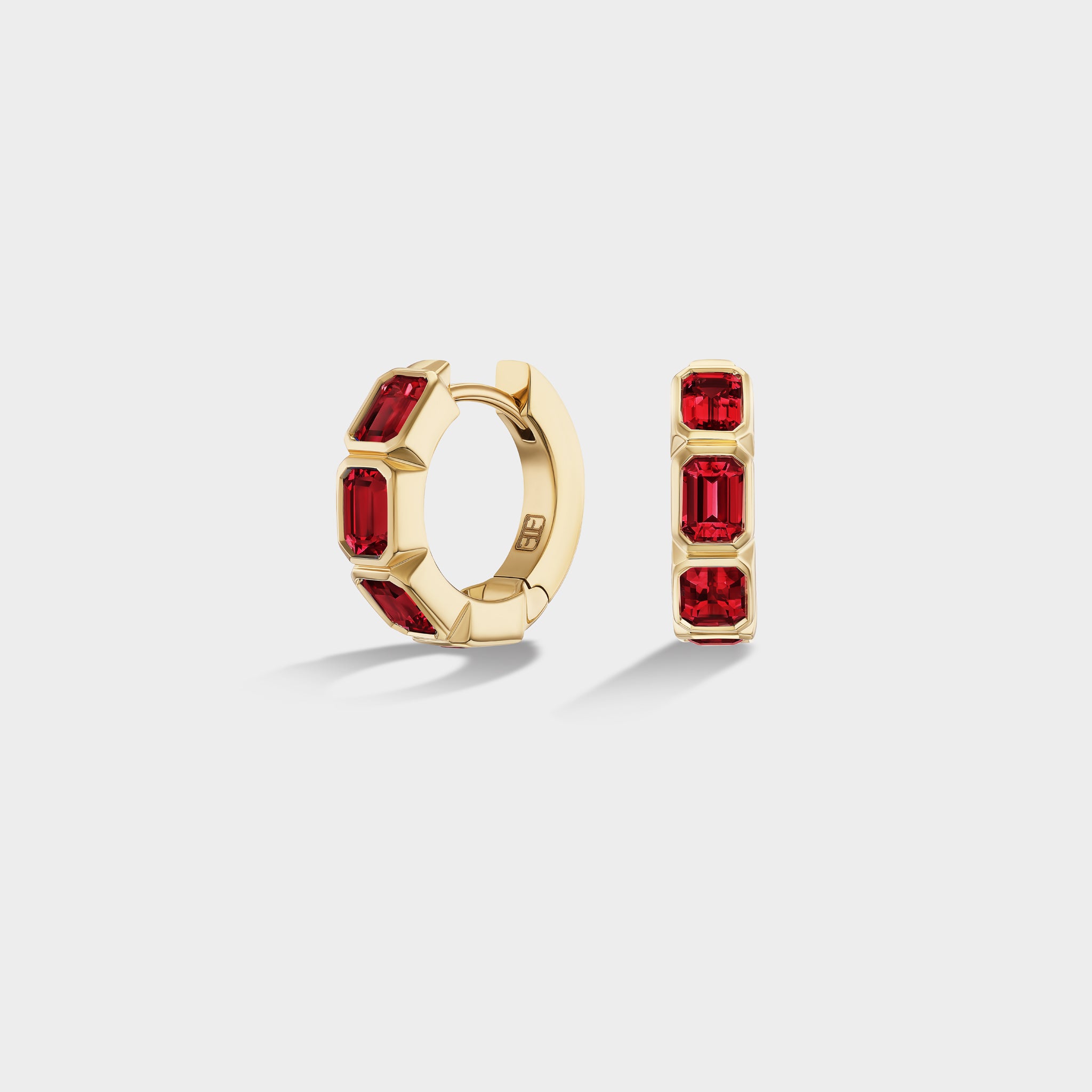 Mini 14K yellow gold huggie hoops with three bezel-set emerald-cut natural rubies, perfect for an ear stack.