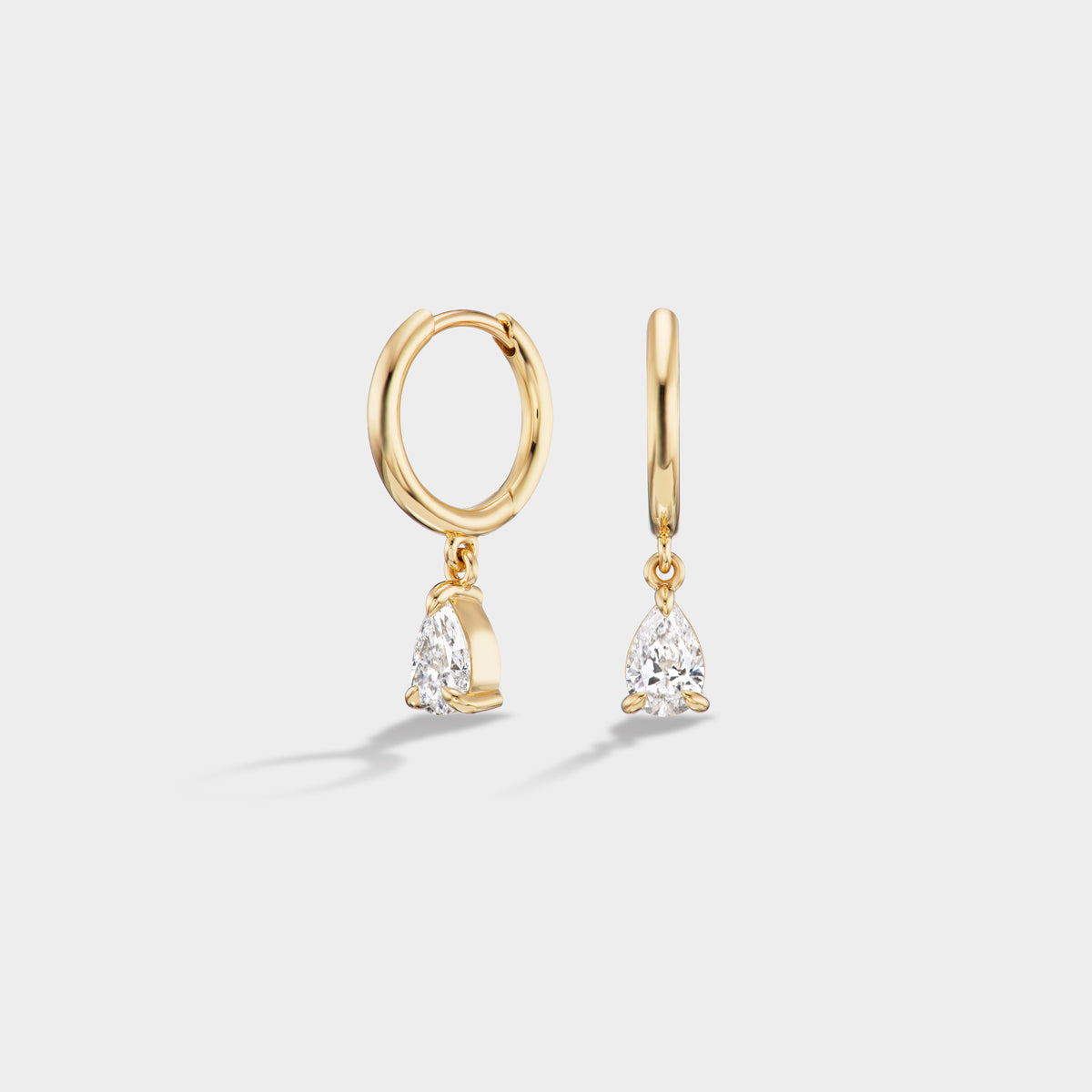 Everyday 14K yellow gold huggie earrings with dangling pear-cut lab diamonds, ideal for stacking.