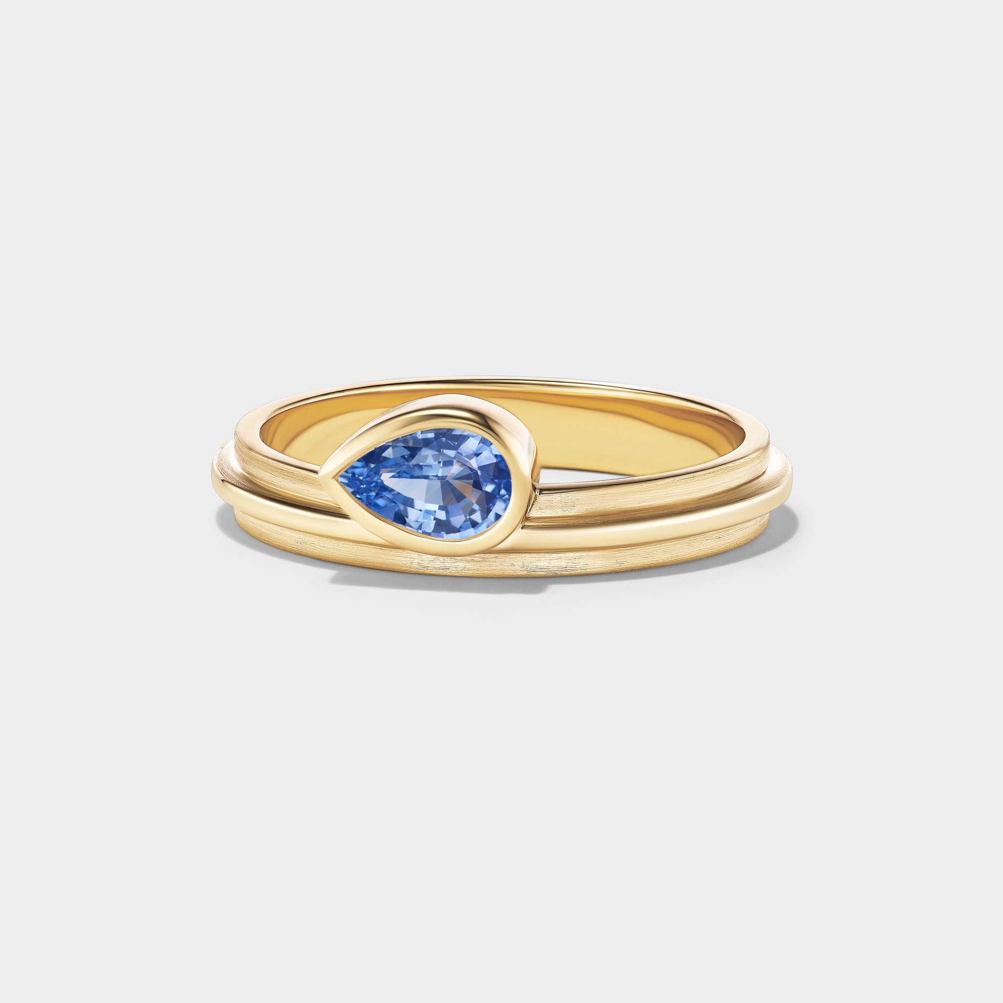 14K yellow gold stacking ring with a pear-cut blue sapphire in a triple-bezel setting.