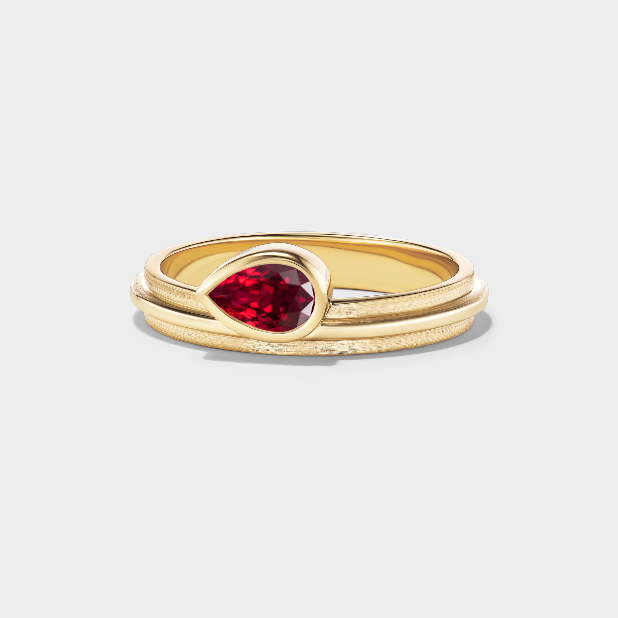14K yellow gold stacking ring with a pear-cut ruby in a triple-bezel setting, perfect for everyday wear.