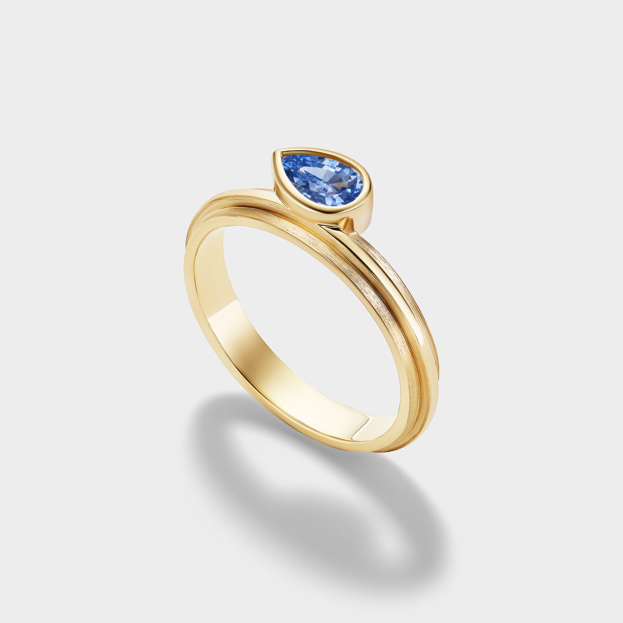 14K yellow gold Pear Lovers Ring with a natural pear-cut blue sapphire in a triple-bezel setting.