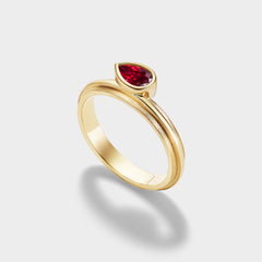 14K yellow gold stacking ring with a pear-cut ruby in a triple-bezel setting, perfect for everyday wear.