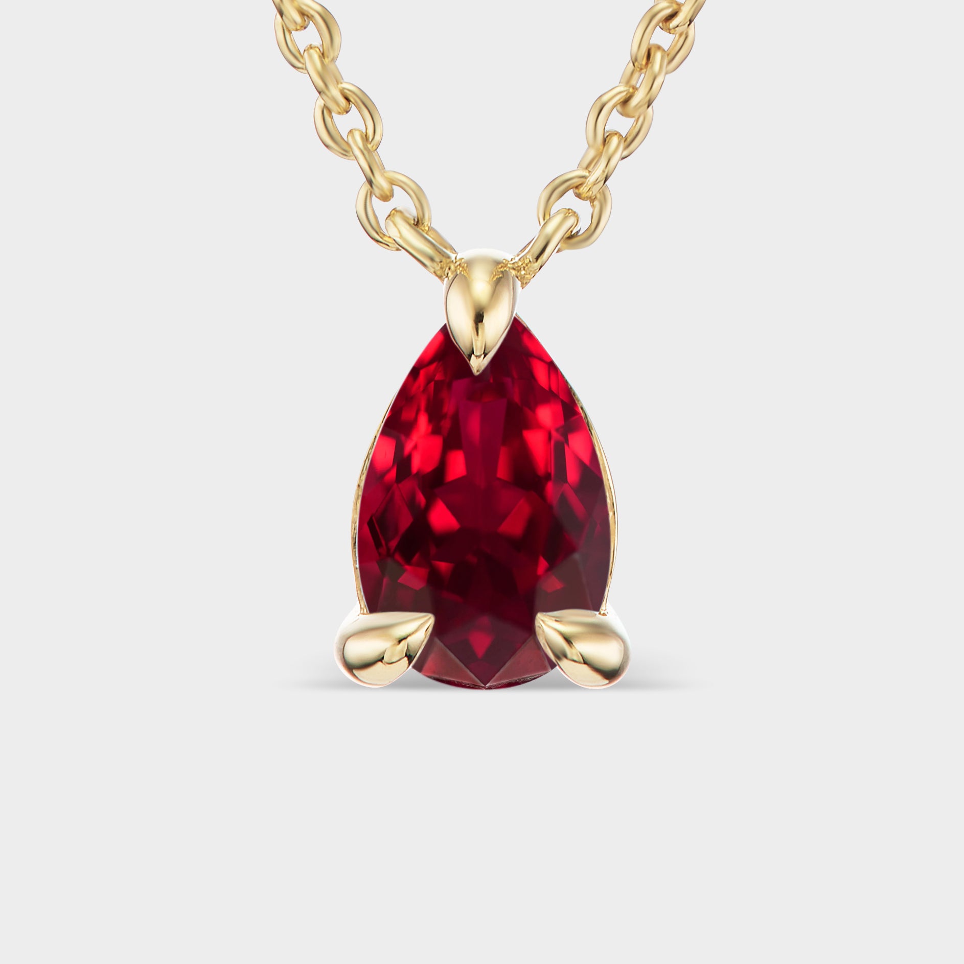Minimalist 14K yellow gold necklace with a pear-cut Tanzanian ruby in delicate prongs, perfect for every occasion.