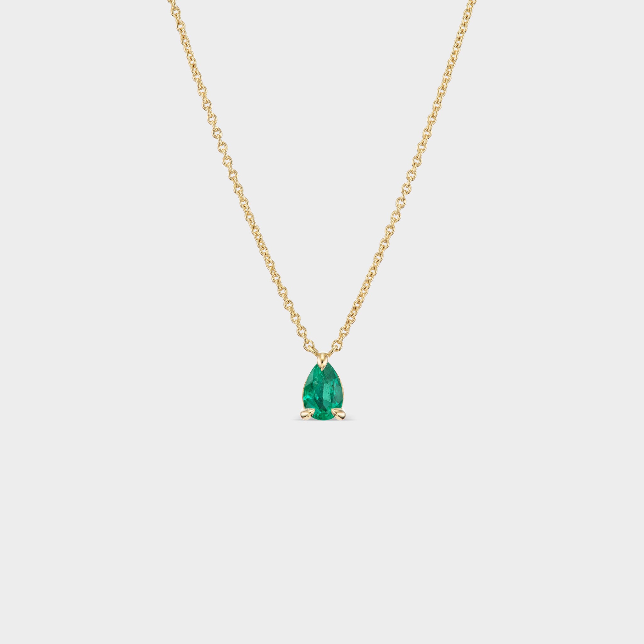 Minimalist 14K yellow gold necklace with a pear-cut green emerald in delicate prongs, perfect for everyday wear.
