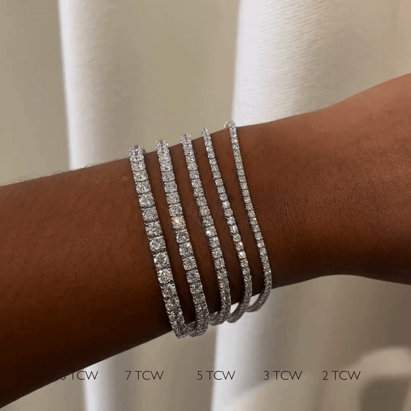 A hand models five 14k white gold lab-grown diamond tennis bracelets, ranging from 2 to 7 TCW, perfect for everyday wear or black tie.